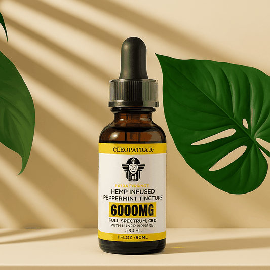 Cleopatra hemp infused peppermint tincture 6000mg full spectrum CBD bottle with dropper on beige surface with green leaves background